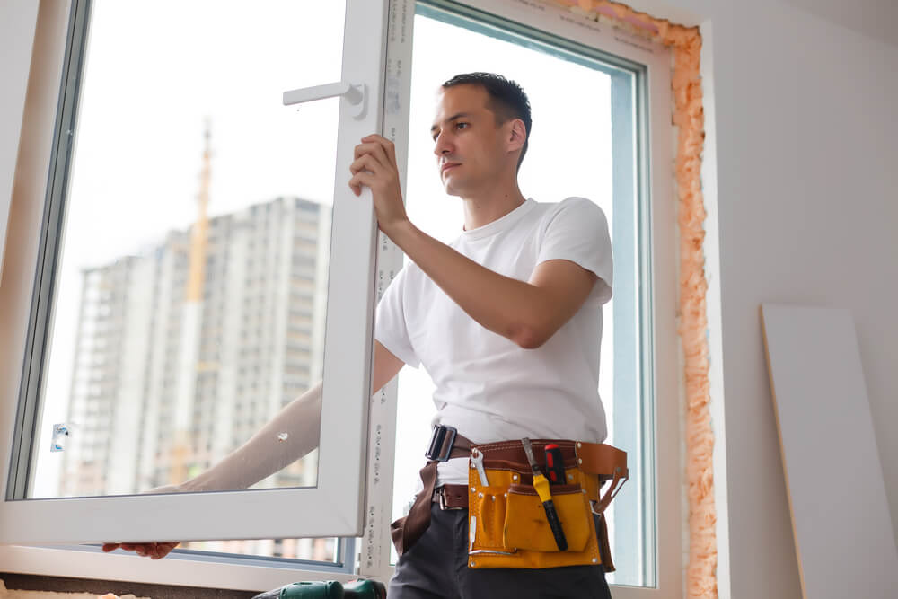 A handyman is repairing a window at home.